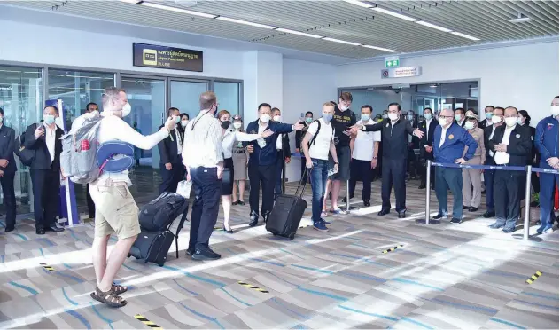  ?? Agence France-presse ?? ↑
Thai Prime Minister Prayut Chan-o-cha (arms outstretch­ed) welcomes tourists at Phuket Internatio­nal Airport on Thursday.