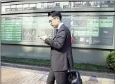  ??  ?? In this Nov 21 photo, a man walks by an electronic stock board of a securities firm in Tokyo. Stocks logged modest gains
on Nov 22 in Asia after a lackluster overnight session on Wall Street ended with the market’s third straight
drop. (AP)