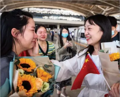  ?? CHENG MIN / XINHUA ?? Wu Weijuan (right), a medical worker from Jiangsu province, wipes the tears of Dong Xuan, who welcomes her at a train station in Wuhan, Hubei province, on Oct 1. Dong, a health worker in Wuhan, fought COVID-19 with Wu, who came to aid the city’s fight against the disease. Wu was among other medical workers from Jiangsu who visited Wuhan during the National Day holiday.