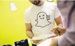  ?? PATRICK T. FALLON / BLOOMBERG FILES ?? Computing services continue to be Snapchat’s biggest expense. Above, a Snap Inc. rep wears a Snapchat shirt while reviewing a resumé during a job fair.