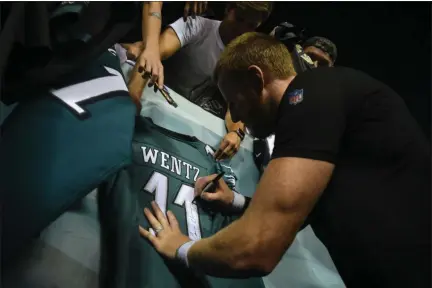  ?? MIKEY REEVES – FOR MEDIANEWS GROUP ?? Above, Eagles quarterbac­k Carson Wentz puts his autograph on a jersey for fans gathered at the Eagles’ practice at Lincoln Financial Field Sunday night. Below, Kamu Grugier-Hill, knocked down by a knee sprain last week, made his way onto Lincoln Financial Field.