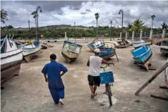  ?? AP PHOTO/RAMON ESPINOSA ?? Fishermen inspect their boats after they were removed from the bay to avoid damage from the passage of Tropical Storm Elsa in Havana, Cuba, on Monday.