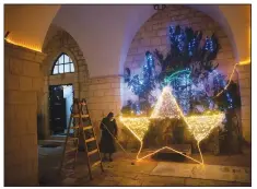  ?? (AP/Oded Balilty) ?? A nun cleans the floor Dec. 12 after decorating the entrance to a church with Christmas lights in Jerusalem’s Old City.