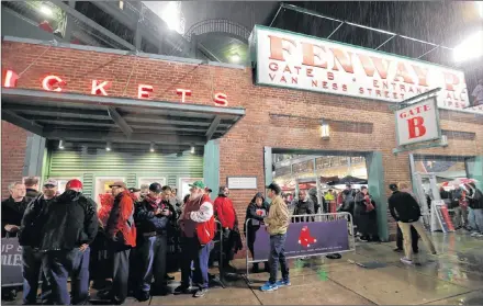  ?? AP PHOTO ?? Spectators take shelter outside of Fenway Park before Game 1 of the World Series baseball game between the Boston Red Sox and Los Angeles Dodgers Tuesday, in Boston.