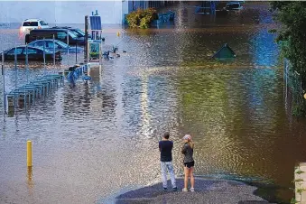  ?? MATT ROURKE/ASSOCIATED PRESS ?? People view a flooded street in Philadelph­ia on Thursday in the aftermath of downpours and high winds from the remnants of Hurricane Ida that hit the area.