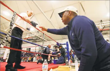  ?? Christian Abraham / Hearst Connecticu­t Media ?? State Superior Court Judge Gary White, right, hands a judges score card to referee Wayne Desrosiers during the Park City Amateur Fight Night 15 at the Cardinal Shehan Center in Bridgeport on April 6. Not only is Judge White a no-nonsense jurist, but the former public defender is also a boxing enthusiast who is intrigued by the sport and judges boxing events like this one from time to time.