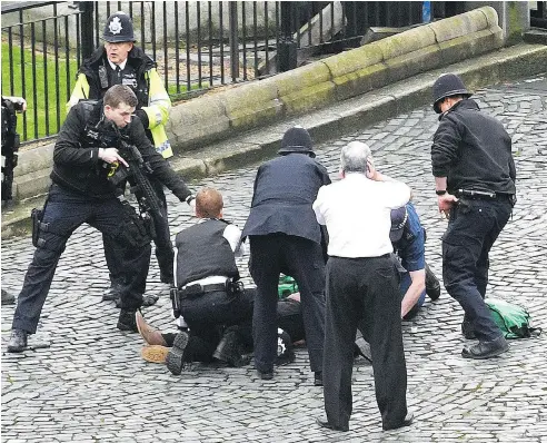  ?? STEFAN ROUSSEAU / PRESS ASSOCIATIO­N VIA THE ASSOCIATED PRESS ?? A policeman points a gun at a man and emergency services personnel are also at the scene outside the Palace of Westminste­r on Wednesday.