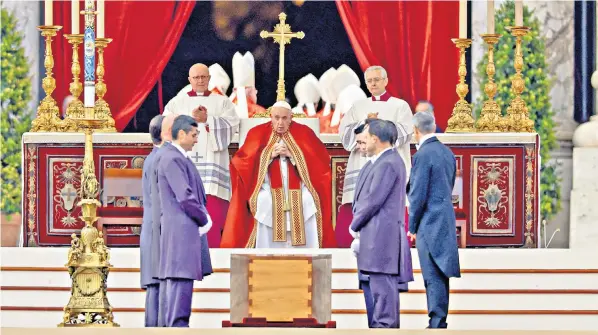  ?? ?? Pope Francis pays tribute to his predecesso­r and, below, Benedict XVI’S coffin