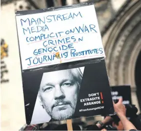  ?? ?? A supporter of WikiLeaks founder Julian Assange holds a placard outside The Royal Courts of Justice, Britain’s High Court, in central London, yesterday. PHOTO: AFP