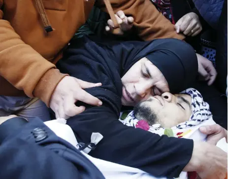  ??  ?? والدة الفلسطيني محمد أمين الذي قتل بعد طعنه جنديا إسرائيليا، تحتضن جثته خالل جنازته قرب الخليل بالضفة أمس. (أ ف ب)