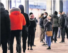  ?? JOE GIDDENS / PA ?? LOOKING FOR A BARGAIN: Socially-distanced morning queues outside Next in Leicester city centre, while left, a woman heads home having bagged a few