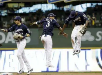  ?? MATT SLOCUM — THE ASSOCIATED PRESS ?? The Brewers’ Lorenzo Cain, Orlando Arcia and Christian Yelich celebrate after Game 1 of the National League Championsh­ip Series Friday in Milwaukee. The Brewers won 6-5 to take a 1-0 lead in the series.