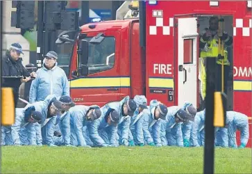  ?? Justin Tallis AFP/Getty Images ?? POLICE in forensic suits search an area in Parliament Square outside the Houses of Parliament in London for any evidence related to the attack Wednesday that killed five people, including the assailant.