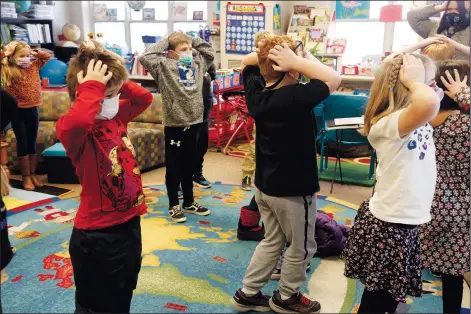  ?? (AP/Martha Irvine) ?? Second-graders hold their heads Dec. 2 as they talk about “thoughts” and how they compare with “feelings” and resulting “actions” at Paw Paw Elementary School in Paw Paw, Mich. Their teacher is one of many in the school trained to use a curriculum created at the University of Michigan called TRAILS. Research suggests TRAILS lessons for at-risk kids can reduce depression and improve coping skills — something district officials say has been particular­ly important during the pandemic.