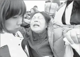  ?? AHN YOUNG-JOON/ASSOCIATED PRESS ?? A relative of a passenger aboard the sunken ferry Sewol in the water off the southern coast weeps as she waits for informatio­n about the missing in Jindo, South Korea on Saturday.