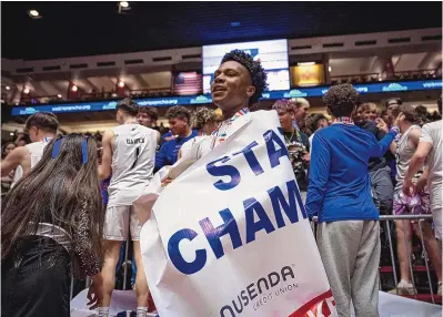  ?? CHANCEY BUSH/JOURNAL ?? Volcano Vista senior Lazerik Hill wraps the championsh­ip banner around himself after the Hawks defeated Sandia in the 5A boys state championsh­ip game on Saturday night at the Pit. It was the second title in a row for VVHS.