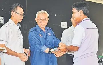  ??  ?? Talib (second left) presents the BR1M voucher to a villager, as Mataip (left) looks on.