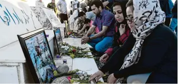  ??  ?? Afghanen legen an einer Gedenkstät­te in Kabul Blumen für die Opfer des Massakers ab.