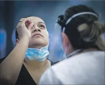  ?? Irfan Khan Los Angeles Times ?? GLENDA GUERRA swabs her nose for a coronaviru­s test, watched over by San Bernardino County Health Department nurse Elizabeth McKinnon, last week in Ontario. California now leads the nation in total cases.