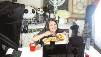  ?? Star Tribune-Tribune News ?? Tassie Yang, who started watching meokbang videos after her personal trainer suggested she try a no-carbohydra­te diet, filmed a video with food from Sweet Chow in Minneapoli­s.