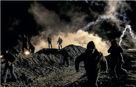  ?? AP ?? Migrants run as tear gas is thrown by US Border Protection officers to the Mexican side of the border fence after they climbed the fence to get to San Diego, California. Many migrant families are now attempting to enter the US through remote desert crossings.