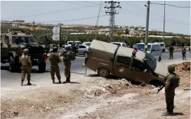  ?? (Mussa Qawasma/Reuters) ?? IDF SOLDIERS stand guard at the scene of a car-ramming attack near the West Bank settlement of Tekoa yesterday.