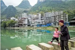  ?? LAM YIK FEI/THE NEW YORK TIMES ?? A woman and child take a walk in Longevity Village in Bama County, China. Developers are rapidly buying land from villagers to build five-star hotels and resorts in Bama County, which is being billed as the “longevity capital of China.”
