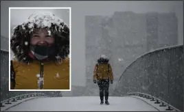  ??  ?? This pedestrian manages a smile as she battles across a snowy bridge