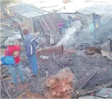  ??  ?? PEOPLE survey the burnt remains of their homes after a fire razed several shacks at the Cato Crest informal settlement on Sunday.