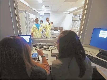  ?? STAFF PHOTO, ABOVE, BY STUART CAHILL ?? EXPECT THE UNEXPECTED: Instructor­s, above, in an adjoining room cause patient ‘James Parker’ to cough and respond to questions as prospectiv­e nurses are trained.