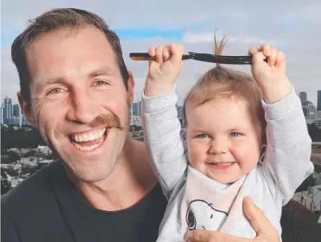  ??  ?? Former Collingwoo­d AFL player Travis Cloke with his daughter Scarlett and his half-shaved moustache. Picture: ALEX COPPEL