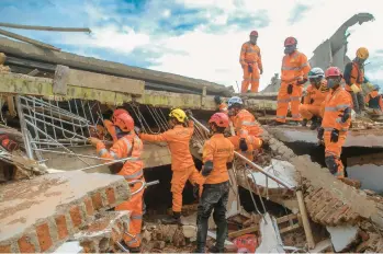  ?? TIMUR MATAHARI/GETTY-AFP ?? Indonesia earthquake: Rescue workers look for victims under collapsed buildings on Tuesday in Cianjur, Indonesia, following a powerful earthquake Monday on the island of Java. At least 268 people were killed, a figure expected to increase, and more than 1,000 hurt in the 5.6 magnitude temblor that was felt some 70 miles away in the capital, Jakarta.