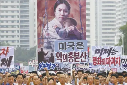  ?? AP PHOTO ?? Tens of thousands of men and women pump their  sts in the air and chant as they carry placards with anti-american propaganda slogans at Pyongyang’s central Kim Il Sung Square on June 25, 2017, in North Korea to mark what North Korea calls “the day of...