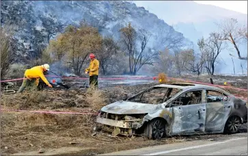  ?? Dan Watson/The Signal ?? Fire investigat­ors look for evidence around a burned-out car that started a 25-acre brush fire on Bouquet Canyon Road near Spunky Canyon Road on Thursday.