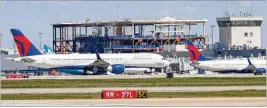  ?? ?? Delta airplanes pass on a taxiway as the new Delta sky lounge is seen under constructi­on by Concourse D. The transport of the first prefab concourse piece is tentativel­y scheduled for the wee hours of April 24.