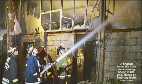  ?? JOVEN CAGANDE ?? A fireman trains his hose on a burning house in Sta. Ana, Manila on Saturday night.