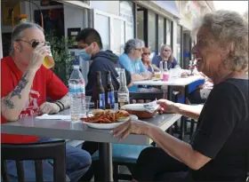  ?? KATHY WILLENS — THE ASSOCIATED PRESS ?? MaryAnn Pereless, right, and Rocky Corivano, join others as the pair had drinks and lunch outdoors at Billy’s Beach Cafe, Wednesday, June 10, in Long Beach, N.Y., on the first day of phase two of the state’s reopening plan in Long Island during the current coronaviru­s outbreak.