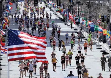  ?? AP/CHARLES KRUPA ?? Runners head down the stretch toward the finish line during the 121st Boston Marathon on Monday. Temperatur­es reached the mid70s, which made it a little more difficult for participan­ts to complete the 26.2-mile course.