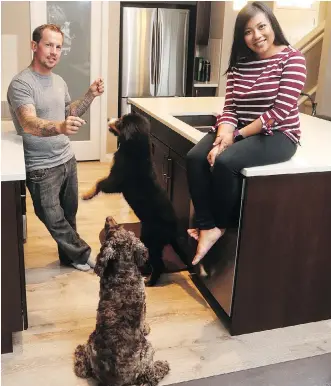  ?? CHRISTINA RYAN ?? Dusten Schneider and Eileen Tria love the spaciousne­ss of their new home in Evanston. Their pooches Cooper and Vada love it too. The couple plan to adopt another dog in the future.