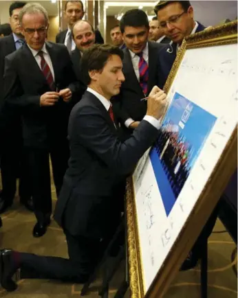  ?? ANADOLU AGENCY/THE ASSOCIATED PRESS ?? Prime Minister Justin Trudeau signs the group photo of the G20 leaders on Sunday. The Liberals have pledged to end the yearlong bombings by CF-18s.