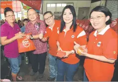  ??  ?? Mayor Chan (second left) with Sports Toto area sales executive Helen Tan (second right) and her team present angpow and goodie bags to an elderly (left).