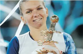  ??  ?? Simona Halep of Romania smiles as she poses for photograph­s holding the trophy for winning the woman’s Madrid Open tennis tournament after defeating Kristina Mladenovic of France.