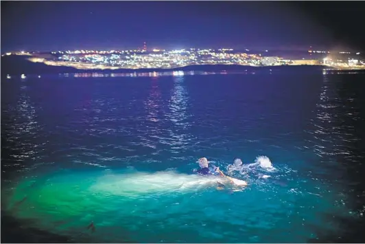  ?? TYLER HICKS THE NEW YORK TIMES LICENSING GROUP / REDUX ?? U.S. Customs and Border Protection agents intercept two swimmers from Mexico trying to reach shore in San Diego. They were tossed a flotation device and water and escorted until they reached the shore break where they were held on the beach. Most, if not all of those caught are deported back to Mexico without charges.