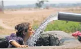  ?? CHANNI ANNAND, AP ?? A girl drinks from an irrigation tube last May in Jammu, India, during a record heat wave when temperatur­es topped 120 degrees.