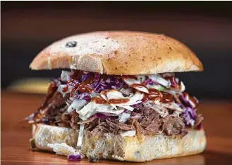  ?? James Nielsen photos / Houston Chronicle ?? Among its traditiona­l offerings, Pinkerton’s Barbecue serves a pulled pork sandwich.