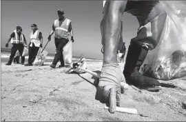  ?? Mel Melcon ?? AT DOCKWEILER State Beach in Playa del Rey, workers pick up debris that officials believe may have come from the Hyperion Water Reclamatio­n Plant.