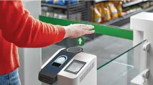  ?? Amazon / AFP via Getty Images ?? A customer waves his hand over Amazon’s palm recognitio­n payment system in Seattle.
