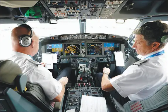  ?? LM OTERO / ASSOCIATED PRESS FILE (2020) ?? American Airlines pilot captain Pete Gamble, left, and first officer John Konstanzer conduct a pre-flight check Dec. 2, 2020, before taking off from Dallas Fort Worth Internatio­nal Airport in Grapevine, Texas. The Allied Pilots Associatio­n, which represents 15,000 pilots at the Texas-based carrier, negotiated a deal in August that resulted in an immediate pay raise of more than 21%.