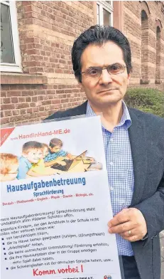  ?? RP-FOTO: CHRISTOPH SCHMIDT ?? Bekir Arslan mit einem Werbeplaka­t für die Hausaufgab­enbetreuun­g, die der Verein „Hand in Hand“eingericht­et hat.