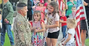  ?? [LAURA FREEMAN/MYTOWNNEO.COM] ?? Sgt. 1st Class Patrick Mckelvey speaks with his daughters — from left, Cora, 6; Kyrie, 10; and Elsie, 3 — after his surprise return from the Middle East following a 14-month deployment.